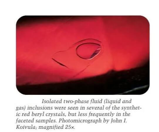 Isolated two-phase fluid (liquid and gas) inclusions were seen in several of the synthetic red beryl crystals, but less frequently in the faceted samples. Photomicrograph by John I. Koivula; magnified 25x.